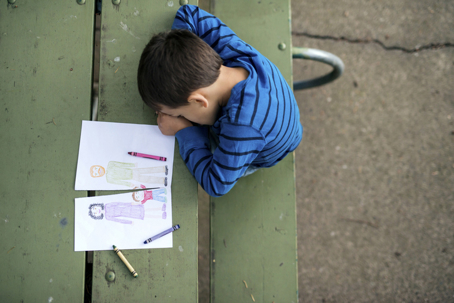 Young boy looking sad at drawing of a broken family stock photo