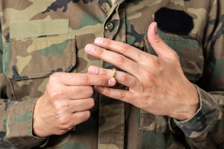 Hands of soldier male who is about to taking off his wedding ring.