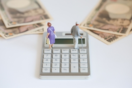 Miniature figures of senior couple, calculator and paper money. Money ima ge of pension, senior couple, retirement, life planning
